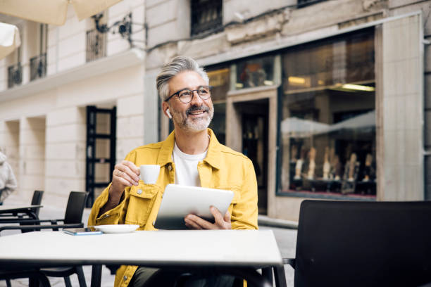 istock Man on vacation enjoying coffee at the cafe and using  tablet 1354249469