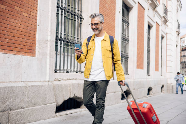 istock Mature man arriving to Madrid and texting on the move 1354249470