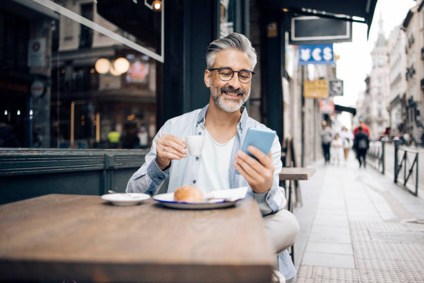 Mature tourist in Madrid taking a break for coffee and breakfast Portrait of a mature tourist in Madrid having coffee and breakfast at the sidewalk cafe and using his smartphone. spanish breakfast stock pictures, royalty-free photos & images