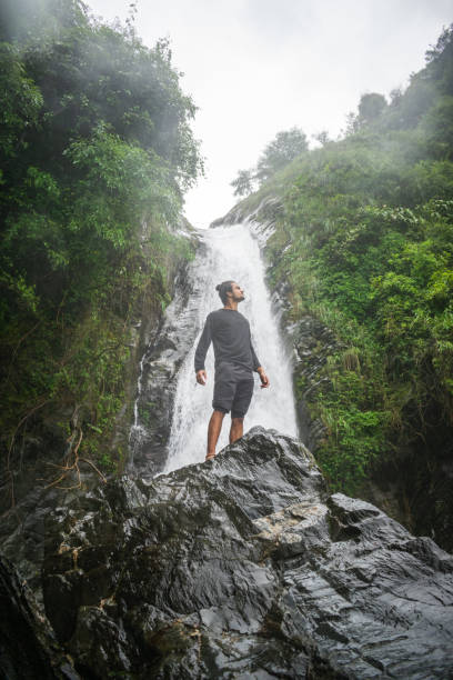 istock young boy standing in front of a waterfall 1354250483