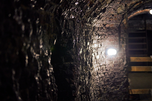 Old brick loft wall in secret military basement. Old wine vault, passageway of mansion. Ancient vintage German fort with dim lighting and brick walls, Kaliningrad