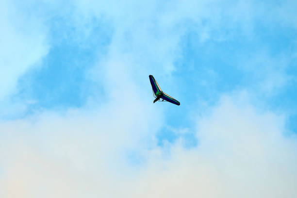 Powered hang glider flying in blue sky, motorized hang glider, ultralight trike overhead view, copy space. Tourist flight on foot-launched powered hang glider. Extreme tourism, extreme sports concept