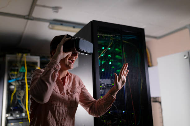 istock Caucasian woman smiling while wearing vr headset touching an invisible screen in server room 1354255058