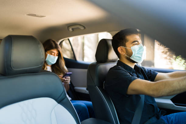 Male driver of a carpool service Handsome man driving a car and working as a rideshare driver during the coronavirus pandemic passenger photos stock pictures, royalty-free photos & images