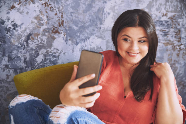 istock Plus size model sitting on the chair and taking a selfie 1354259316