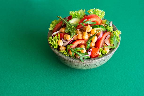 野菜、ハーブ、緑の背景にドレッシングとボウルに健康的なベジタリアンひよこ豆サラダ。 - rainbow peppercorns ストックフォトと画像