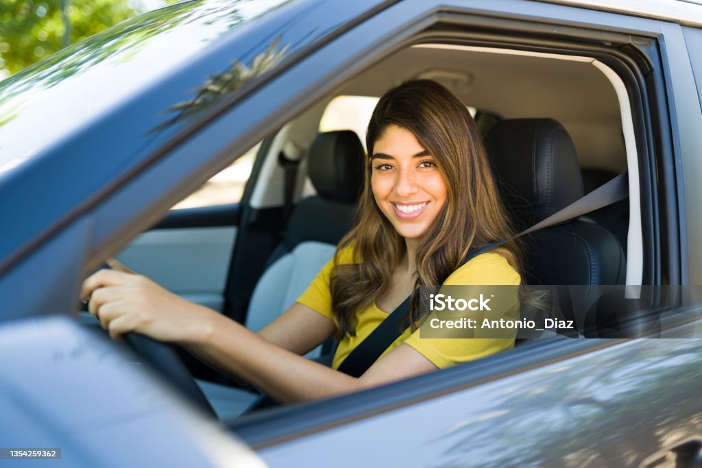 Portrait of a latin woman in the driver's seat Attractive young woman smiling and looking at the camera while driving her new car to work in the morning Crowdsourced Taxi Stock Photo
