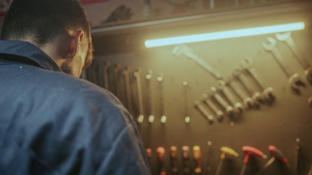 istock Young blacksmith male person picking up his tools from the bench to do work 1354260992