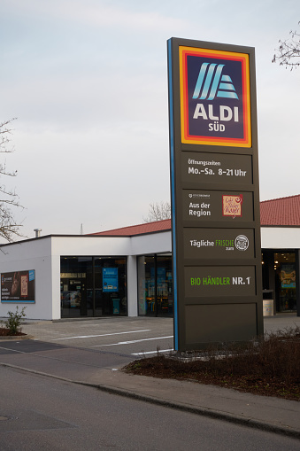 Plochingen, Germany - March 09, 2021: Aldi south column at the roadside, supermarket in the background. Walkway and driveway.