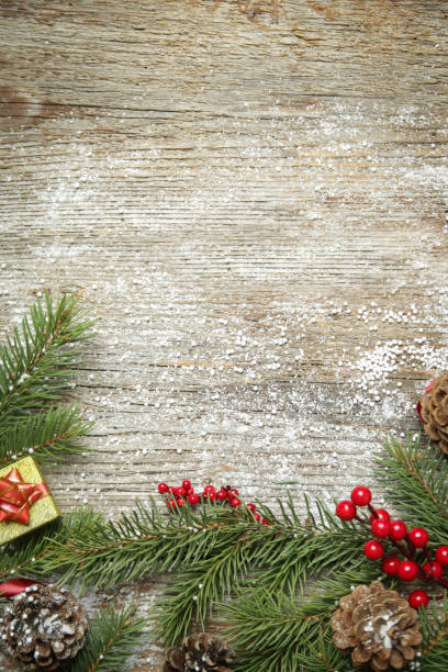 istock Christmas tree branches, gift box, conifer cones and red berries top view with copy space on old wooden background. Christmas, winter holiday, new year concept. 1354262317