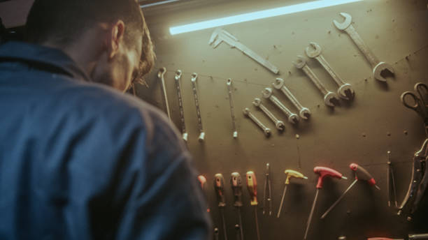 istock Young blacksmith male person picking up his tools from the bench to do work 1354262394