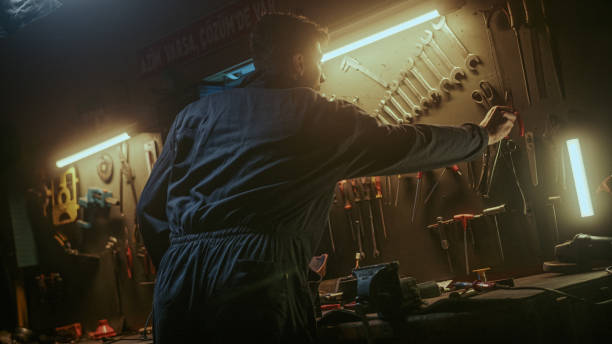 istock Young blacksmith male person picking up his tools from the bench to do work 1354263137