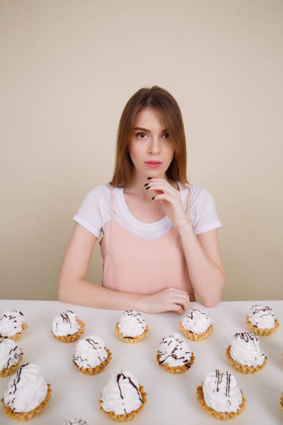 istock Amazing young lady sitting and posing near cupcakes 1354264277