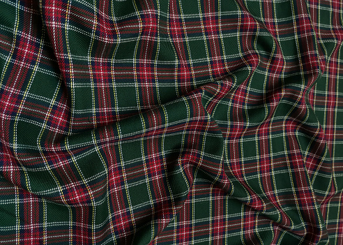 Green tartan woolen school uniform fabric material. Scottish classic seamless flannel cloth. Traditional wave pattern for a Christmas background or wallpaper. Black, Green, Red and White checkered