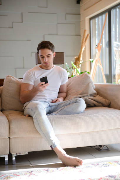 istock Man sitting on sofa with phone 1354268194