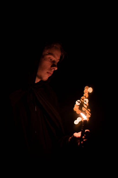 monk portrait human face hold candle fire light and pray in darkness environment space vertical photography soft focus concept