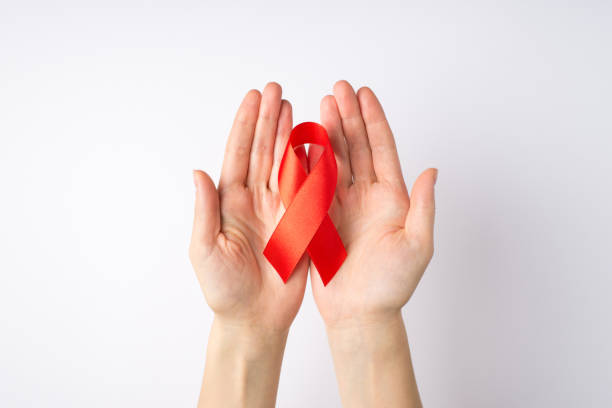 photo de la première personne vue de dessus des mains d’une jeune femme tenant un ruban de soie rouge dans les paumes symbole de la sensibilisation au sida sur fond blanc isolé - hiv photos et images de collection