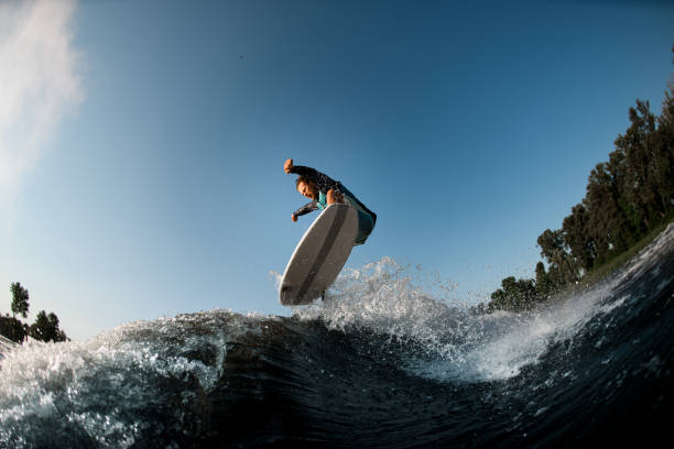 istock Active male wakesurfer jumping on a wake board down the river waves 1354271348