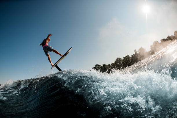 ragazzo attivo che si diverte e cavalca l'onda con l'aliscafo foilboard - wakeboarding nautical vessel wake jumping foto e immagini stock