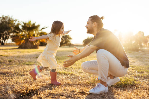 padre e hija jóvenes y despreocupados abrazados en el día de primavera. - action family photograph fathers day fotografías e imágenes de stock