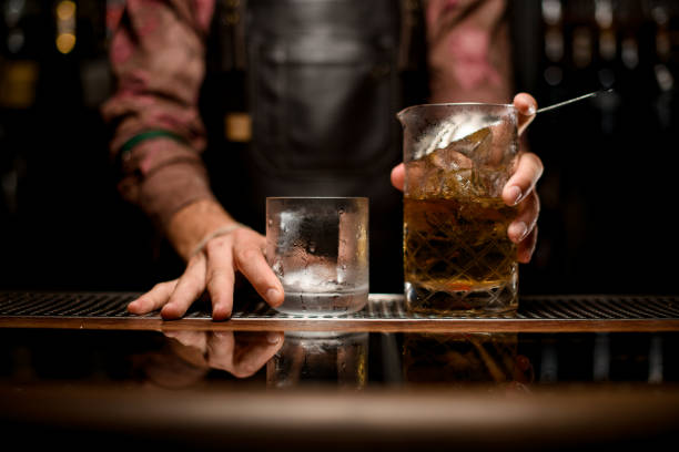 istock empty transparent glass and mixing cup with cold drink on bar counter 1354276550