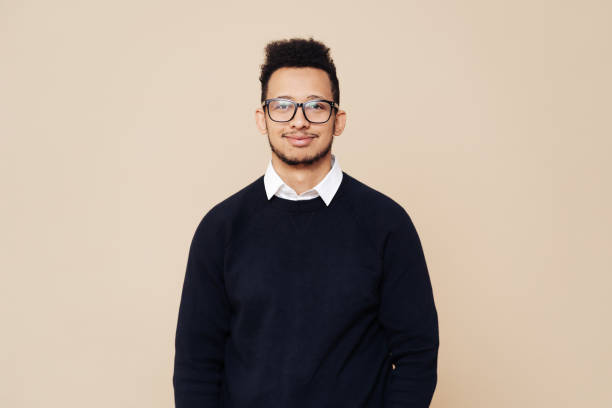istock Afro Good looking guy in black sweater and glasses posing on beige background 1354284412