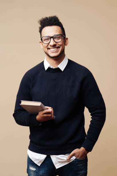 Afro Good looking guy in black sweater and glasses posing on beige background stock photo