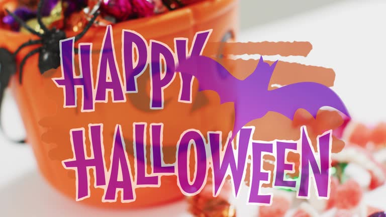 Happy halloween text banner with bat icon against pumpkin shaped bucket full of halloween candies