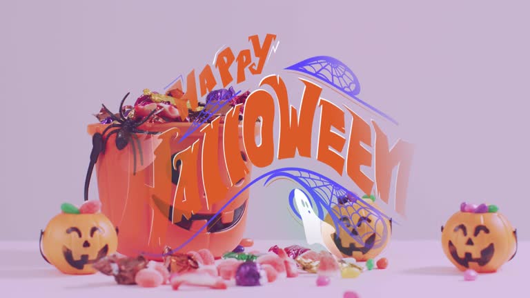 Happy halloween text banner and ghosts icons against pumpkin shaped bucket full of halloween candies