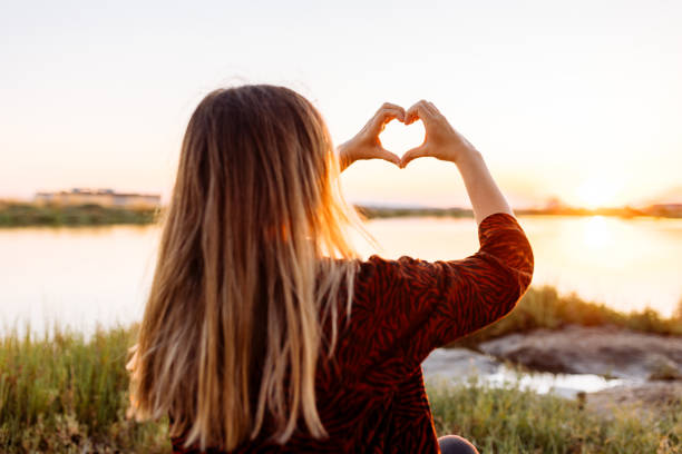 istock Hand shaped heart against beautiful sunset 1354303222