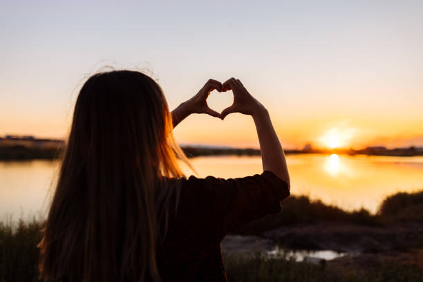 istock Hand shaped heart against beautiful sunset 1354303372