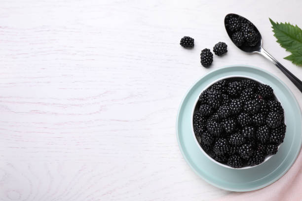 istock Flat lay composition with fresh ripe blackberries on white wooden table. Space for text 1354305487