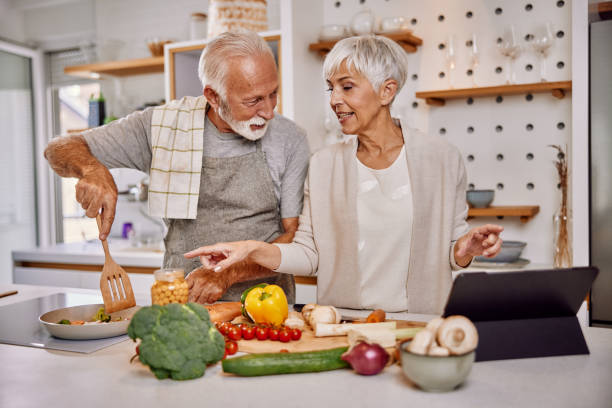 istock Smiling elderly vegan couple preparing a fresh vegetable salad in the kitchen, using a tablet 1354305933