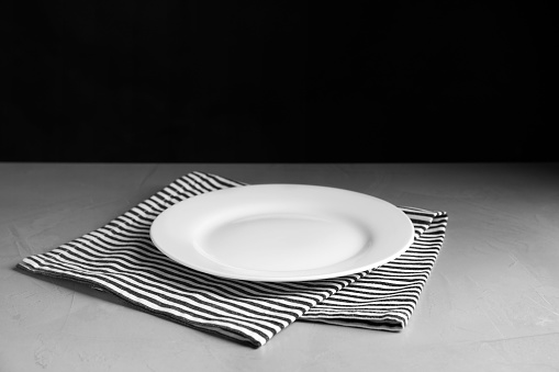 Empty ceramic plate and towel on light grey table