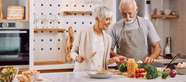 happy and healthy seniors prepare vegan food at home stock photo
