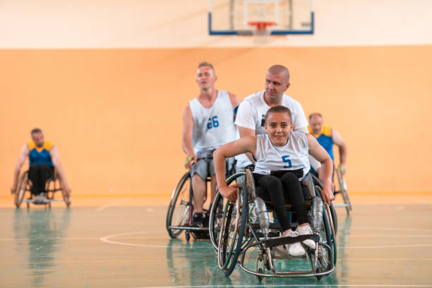 Disabled War or work veterans mixed race and age basketball teams in wheelchairs playing a training match in a sports gym hall. Handicapped people rehabilitation and inclusion concept.Hi quality photo