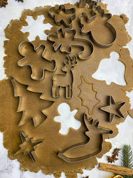 bild von hausgemachtem, lebkuchenkeksteig, der auf marmoreffekthintergrund ausgerollt wurde, metall-weihnachtskeksausstecher, weihnachtsbaum, sterne, rentiere, zuckerstangen- und lebkuchenmänner schneiden formen aus, hausbacken, erhöhte aussicht - candy cane christmas cookie raw food stock-fotos und bilder