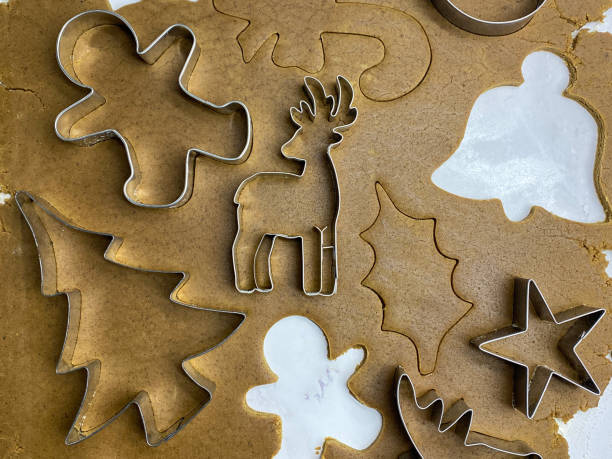 vollrahmenbild hausgemacht, lebkuchen-keksteig auf marmoreffekt-hintergrund ausgerollt, metall-weihnachts-keksausstecher, weihnachtsbaum, stern, rentier, stechpalmenblatt, glocke, zuckerstange und lebkuchen männer schneiden formen aus, hausbacken, erhöht - candy cane christmas cookie raw food stock-fotos und bilder