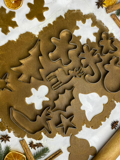 bild von hausgemachtem, lebkuchenkeksteig, der auf marmoreffekthintergrund ausgerollt wurde, metall-weihnachtskeksausstecher, weihnachtsbaum, sterne, rentiere, zuckerstangen- und lebkuchenmänner schneiden formen aus, hausbacken, erhöhte aussicht - candy cane christmas cookie raw food stock-fotos und bilder