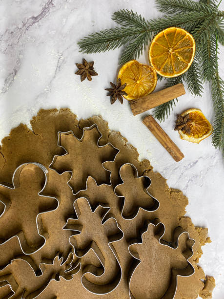 bild von hausgemachtem lebkuchenkeksteig, der auf marmoreffekthintergrund ausgerollt wurde, keksausstecher mit metallweihnachtsmotiven, schneeflocken, rentieren, zuckerstangen und lebkuchenmänner schneiden formen aus, hausbacken, erhöhte aussicht - candy cane christmas cookie raw food stock-fotos und bilder