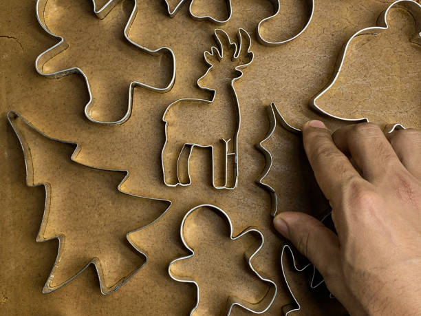 imagen de fotograma completo de masa de galleta casera desplegada, pan de jengibre, persona irreconocible que usa cortadores de galletas de metal con temática navideña, árbol de navidad, reno, hoja de acebo, campana, caña de caramelo y pan de jengibre  - candy cane christmas cookie raw food fotografías e imágenes de stock