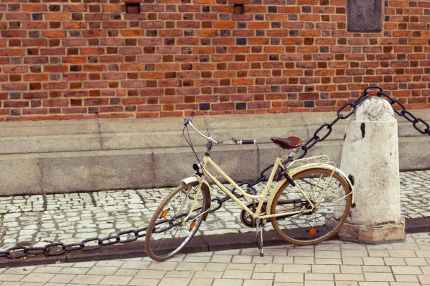Funky hipster creamy white retro bicycle on a street in front of yellow red orange brick wall