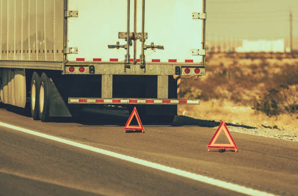 Broken Semi Truck on Side of a Highway Heavy Transportation Theme. Broken Semi Truck on Side of a Highway Trailer Close Up and Warning Triangles. Roadside Asssitance. emergency services equipment stock pictures, royalty-free photos & images