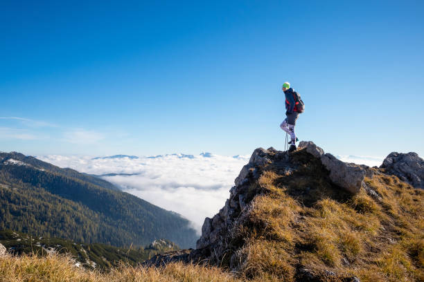 Woman on top of the mountain above the clouds bathing in sunlight.