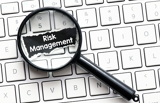 Risk Management concept. A magnifier placed on a keyboard and a black piece of paper with the word risk management on it.