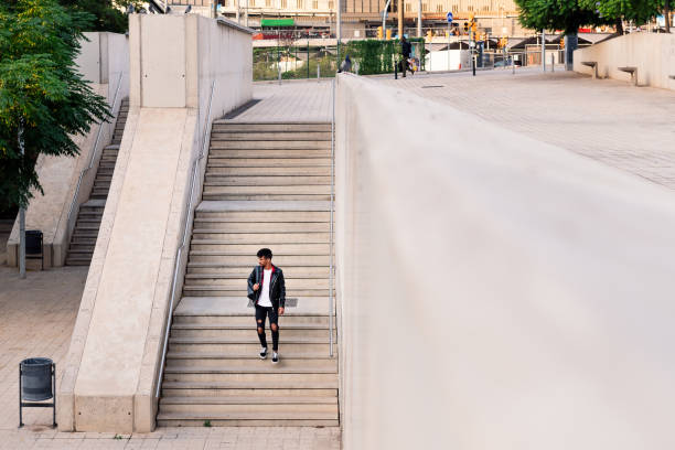 istock young latin man with backpack walking down stairs 1354316705
