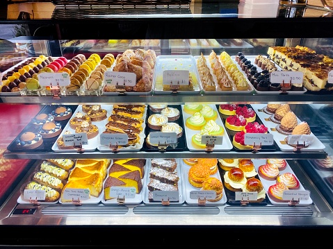 Horizontal closeup photo of a variety of freshly baked French pastries on display in a refrigerated cabinet in a Cafe Patisserie. Armidale, New England high country, NSWm