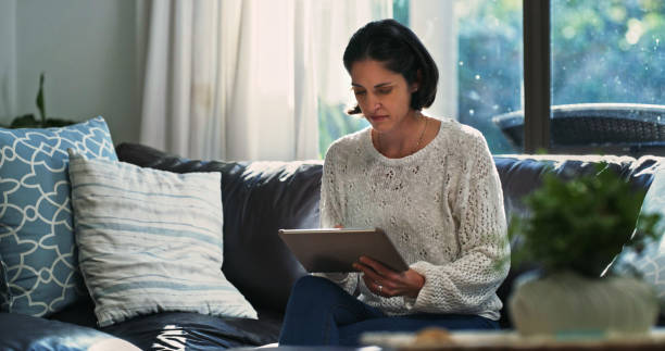 istock Shot of a woman using a tablet on the sofa at home 1354325868