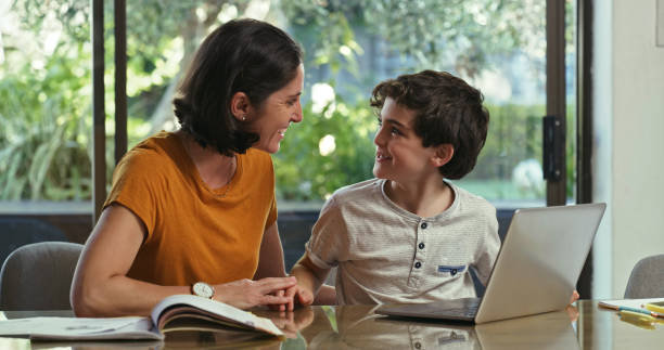 istock Shot of a boy using a laptop while sitting at home with his mother 1354325893