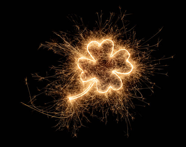 golden bright sparkler four leaf clover luck symbol  isolated on dark black background. silvester new year birthday celebration design pattern